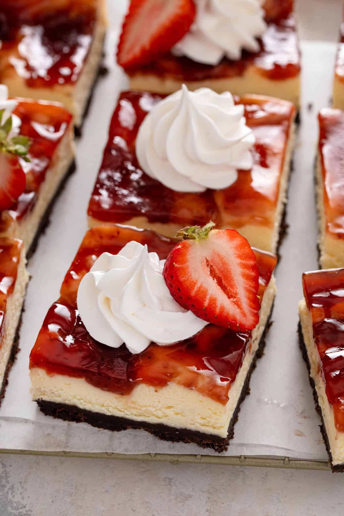 Close up image of sliced strawberry cheesecake bars on a piece of parchment paper.