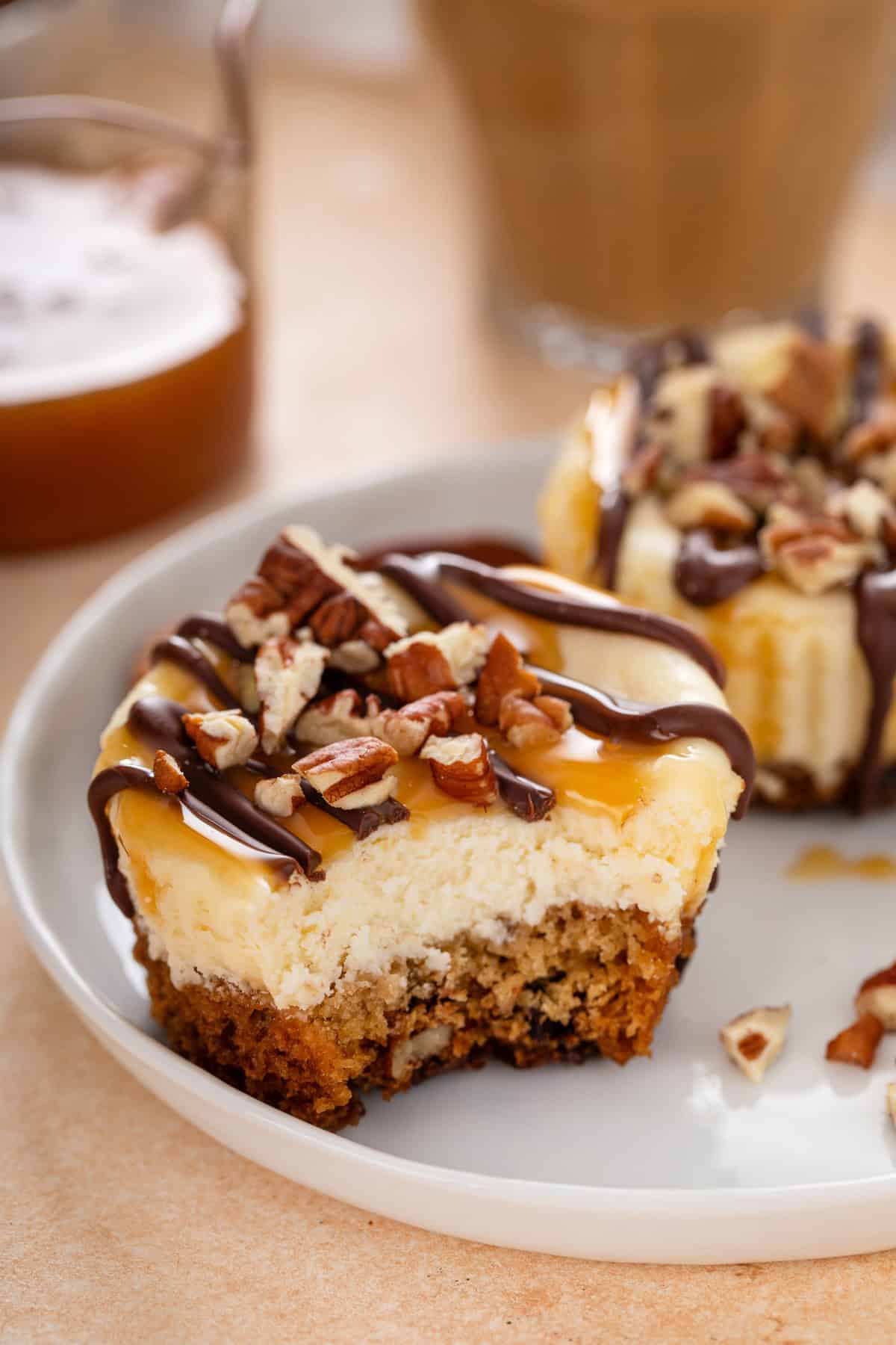 Mini turtle cheesecake on a white plate, with a bite taken from the cheesecake.