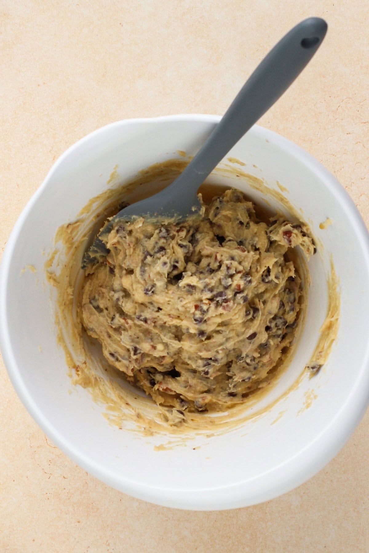 Chocolate chip cookie crust dough in a white mixing bowl.