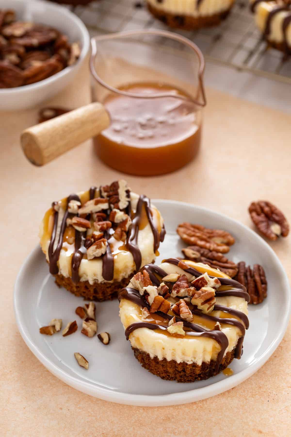 Two mini turtle cheesecakes on a white plate.