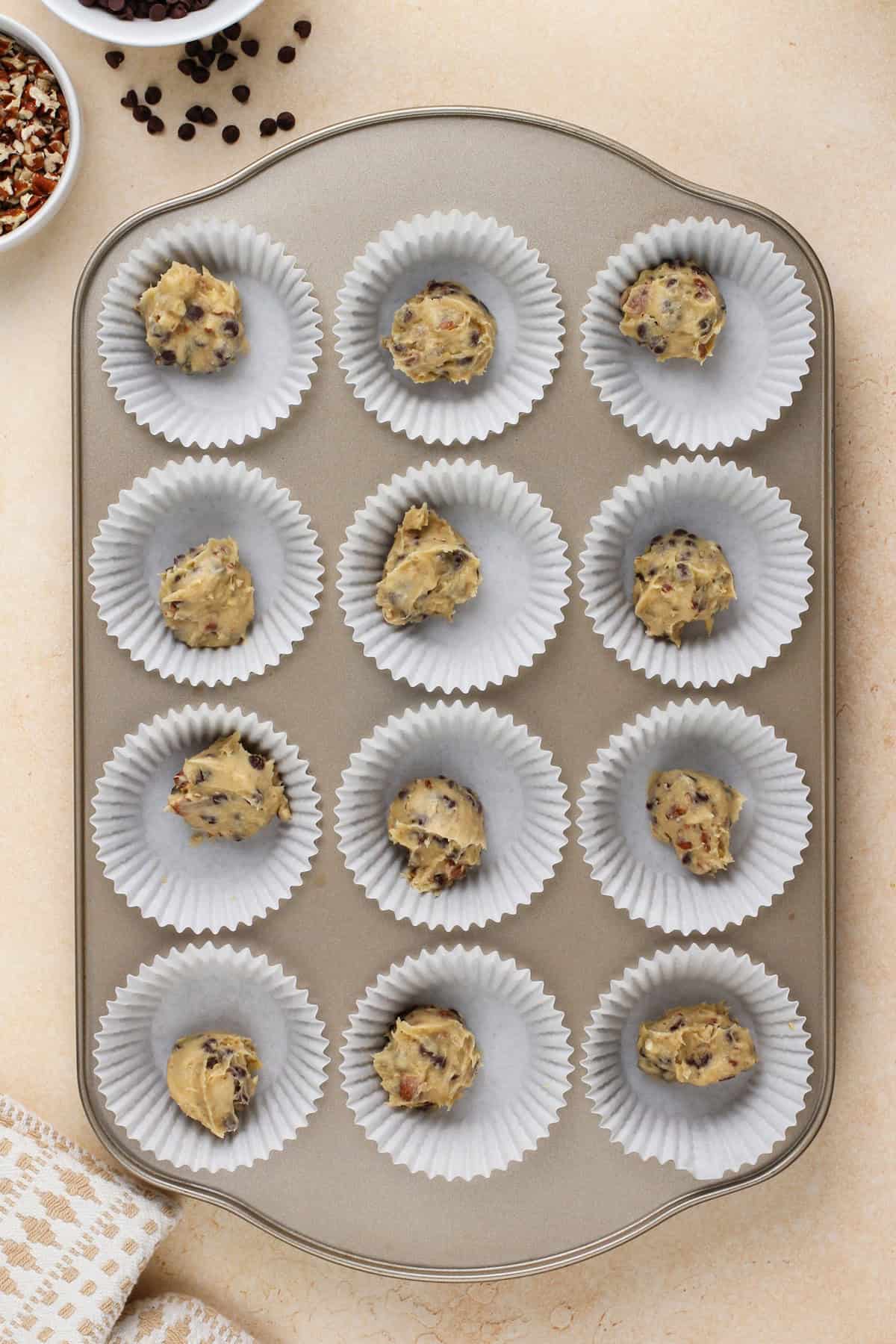 Cookie dough portioned into muffin cups for mini cheesecake crusts.