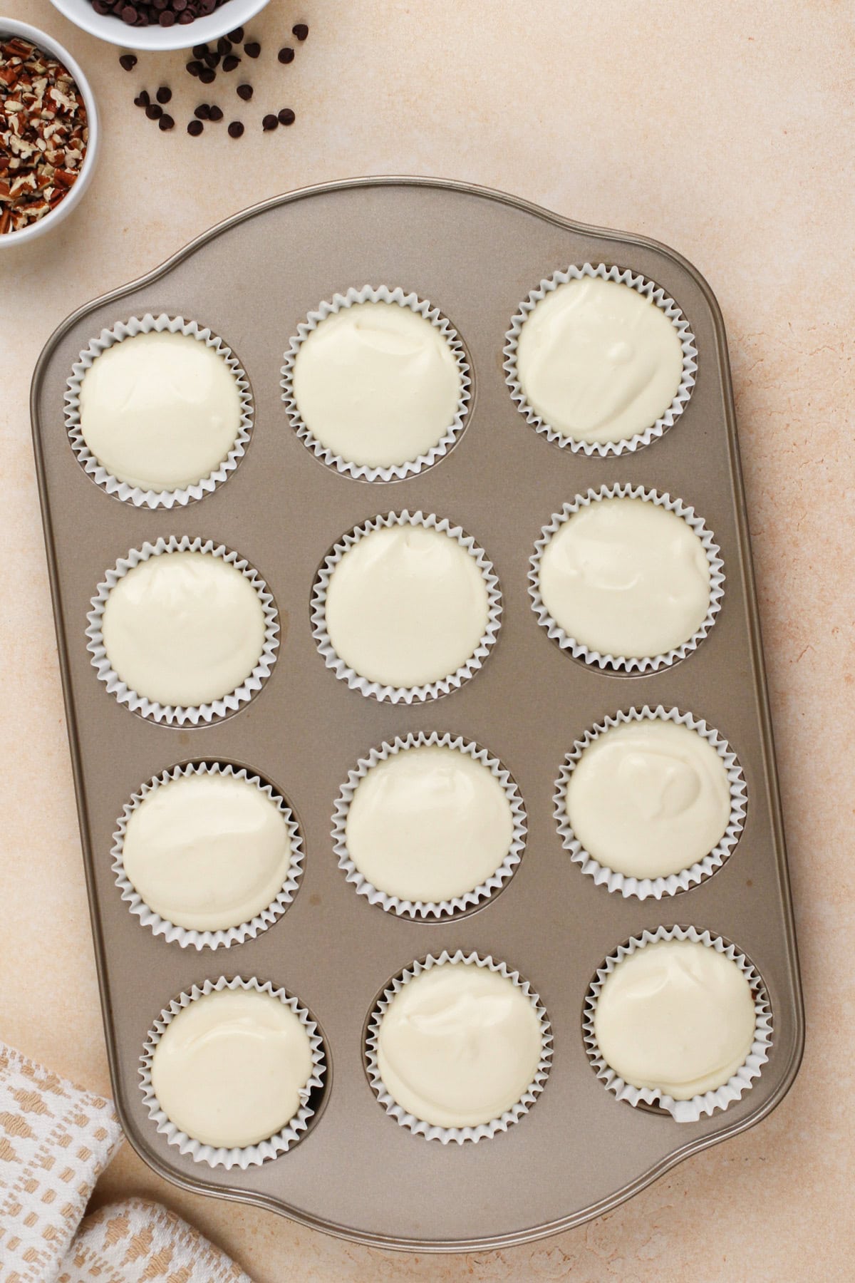 Unbaked mini cheesecakes in a muffin tin, ready to go in the oven.
