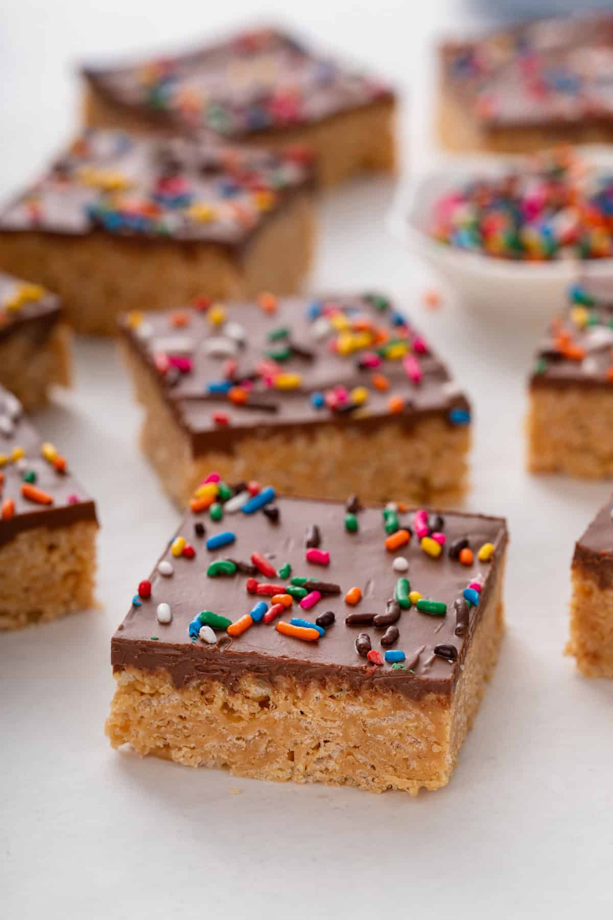 Side view of a sprinkle-topped scotcheroo bar on a countertop with more bars in the background.