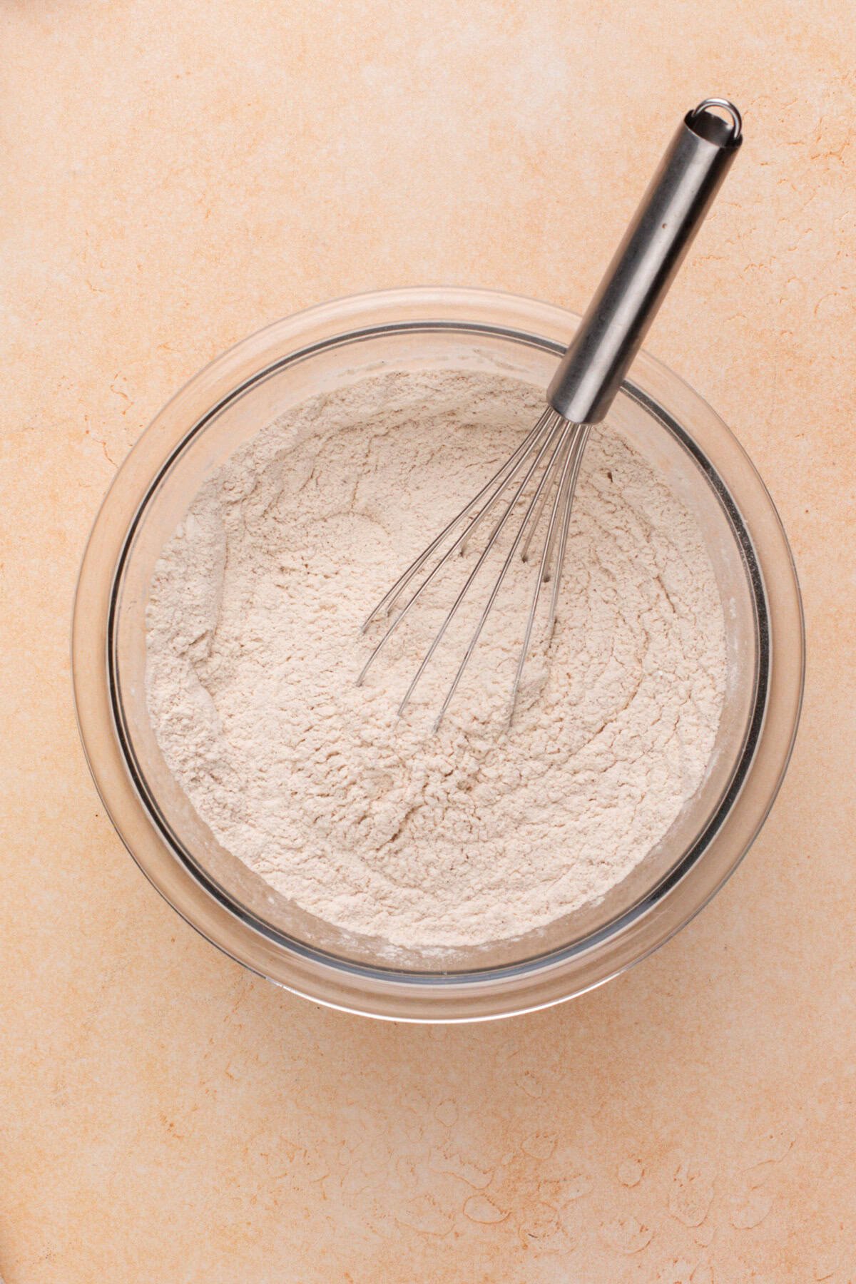 Dry ingredients whisked together in a glass bowl.