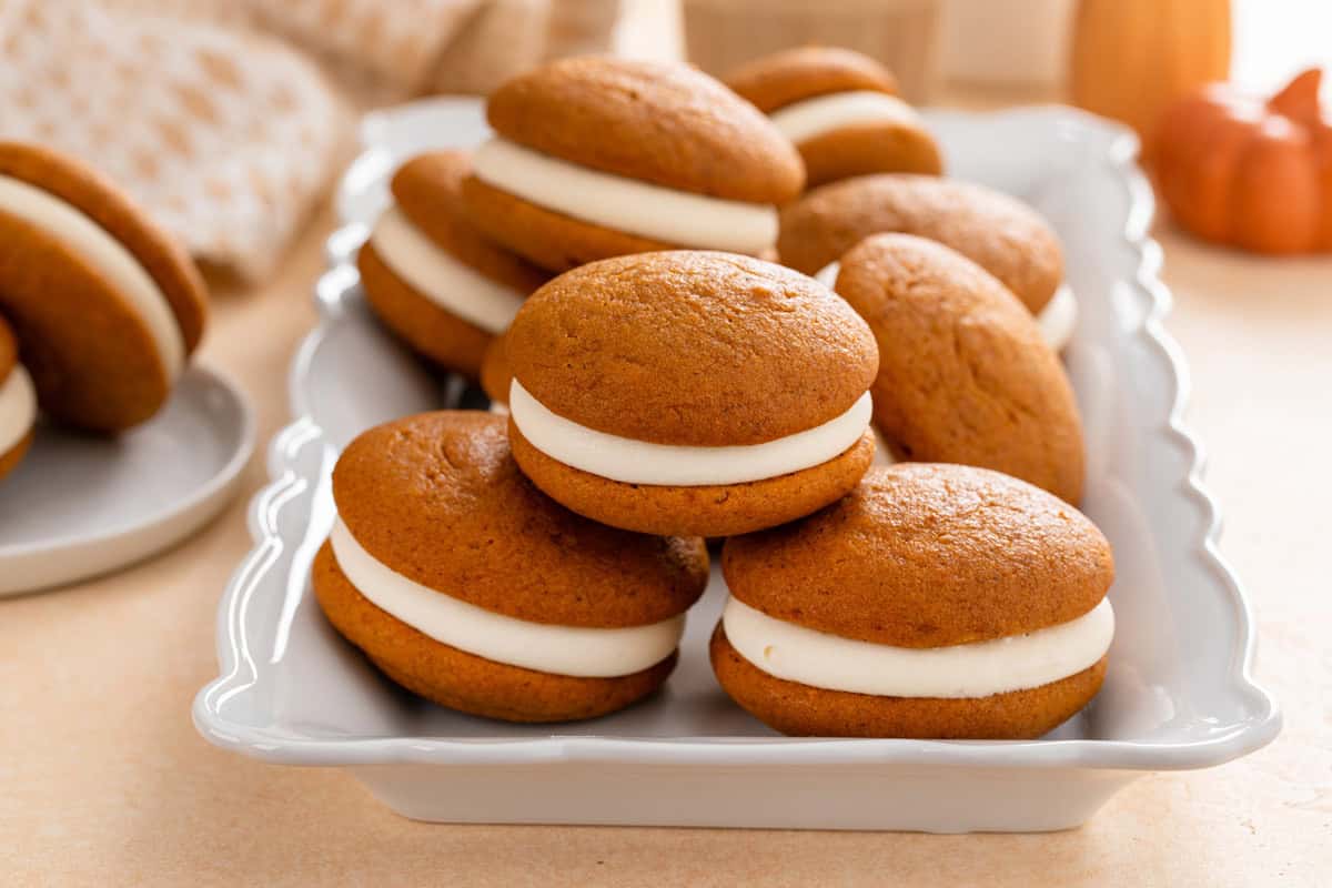 Three pumpkin whoopie pies stacked on a gray platter.