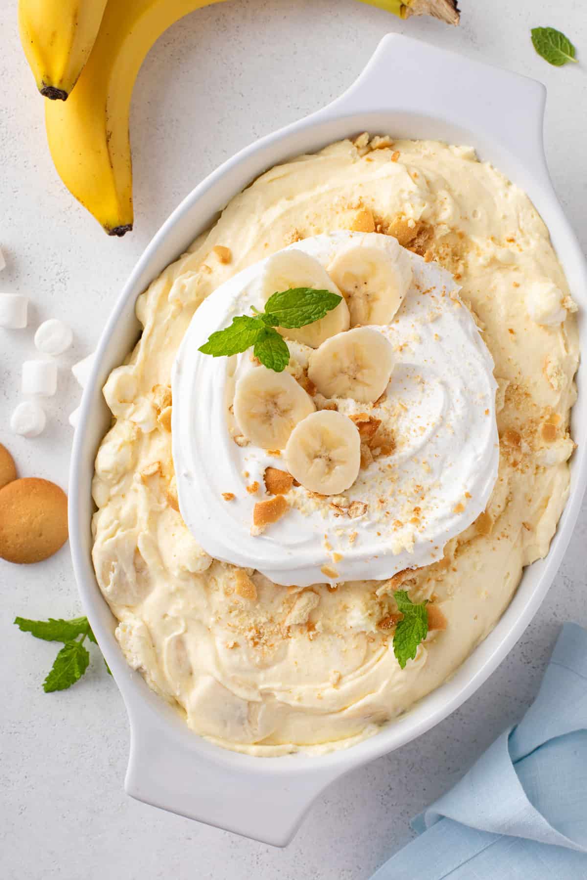 White serving dish filled with banana pudding fluff, garnished with whipped cream and sliced bananas.