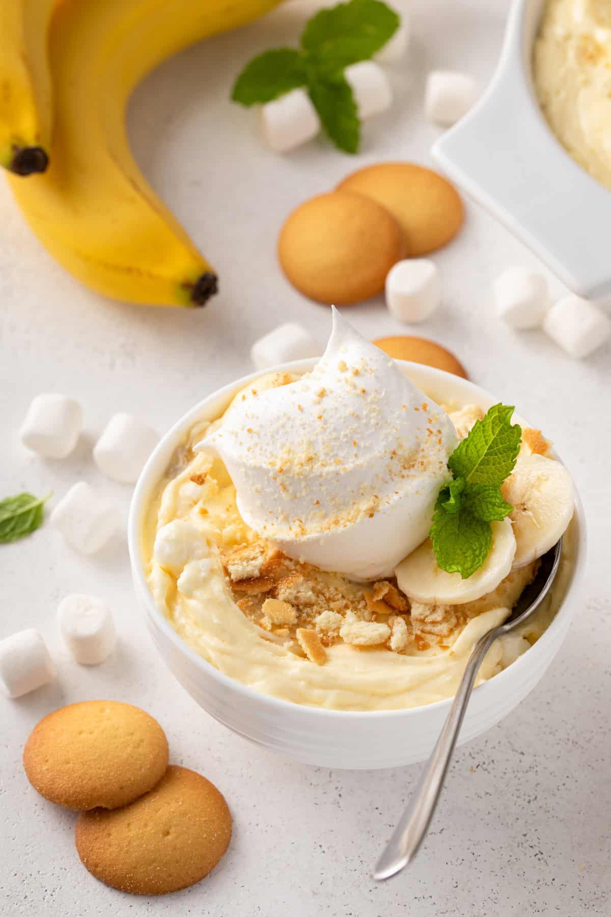 Spoon in a small bowl of banana pudding fluff that's topped with whipped cream.