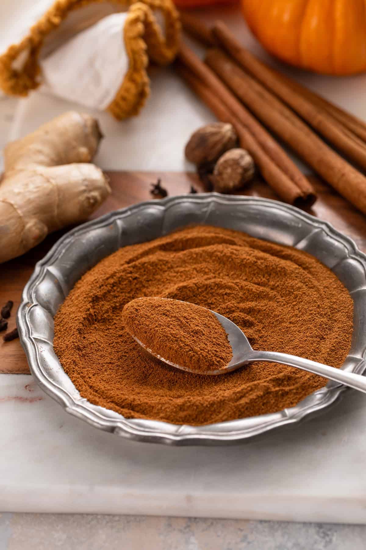 Spoon of pumpkin pie spice resting on a metal plate.
