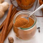 Spoonful of pumpkin pie spice resting on top of a jar.