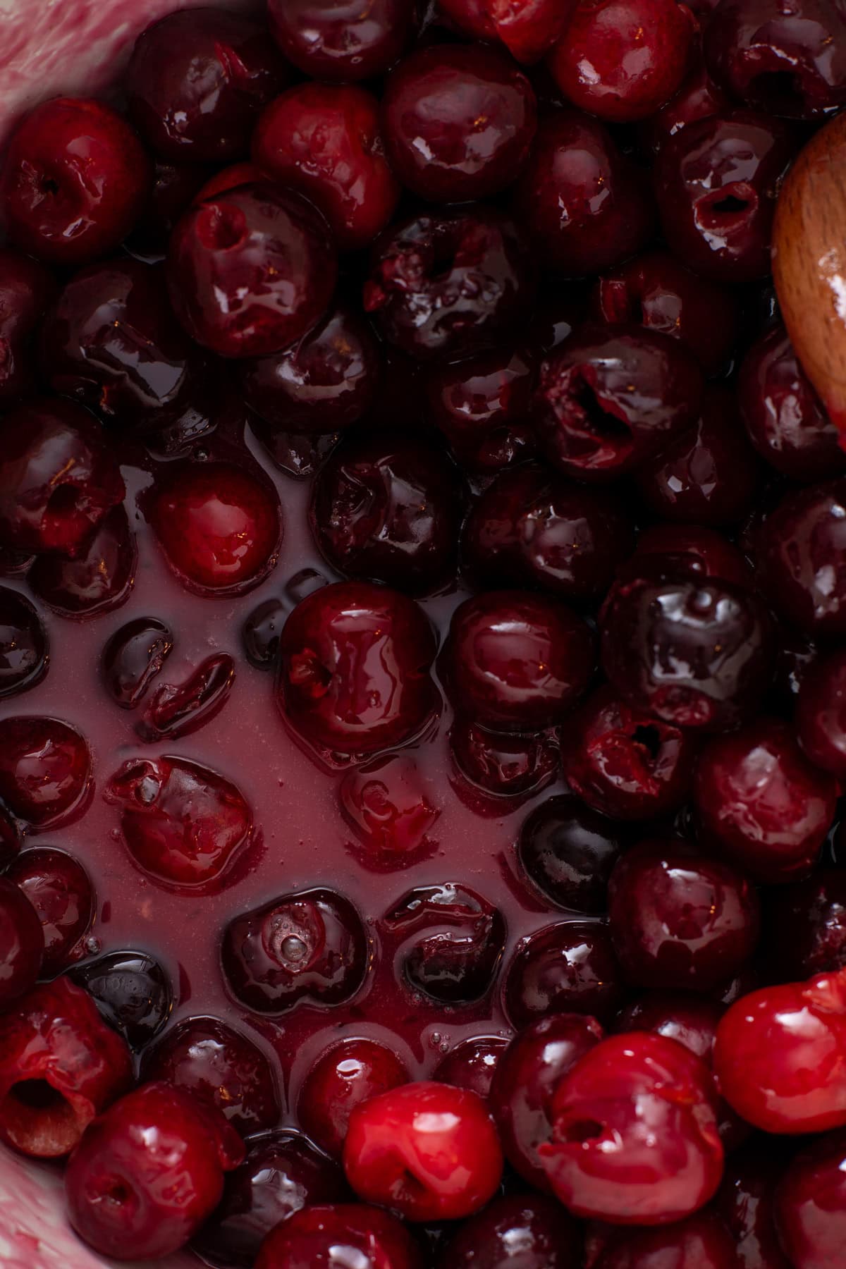 Starting to cook cherry pie filling in a sauce pot.