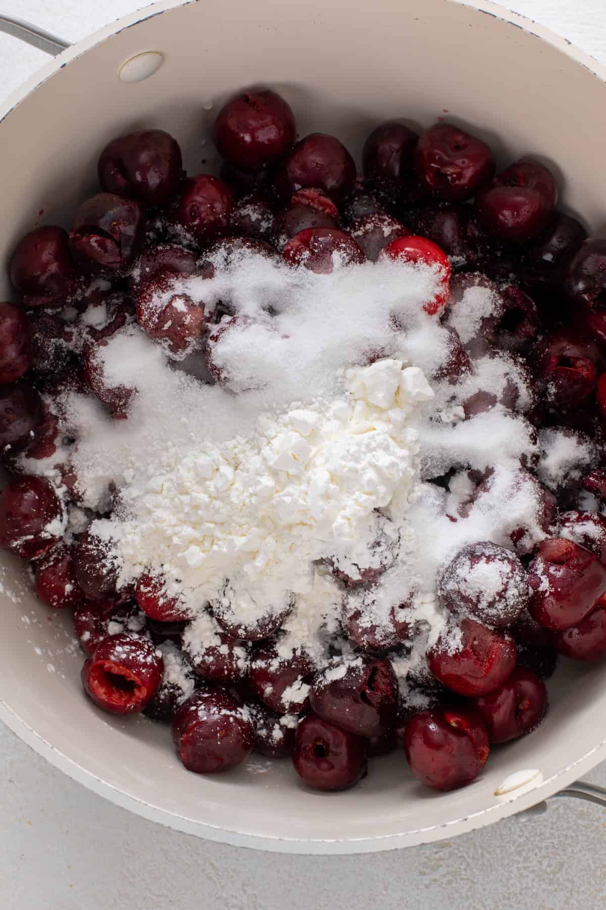 Ingredients for cherry pie filling added to a sauce pot.