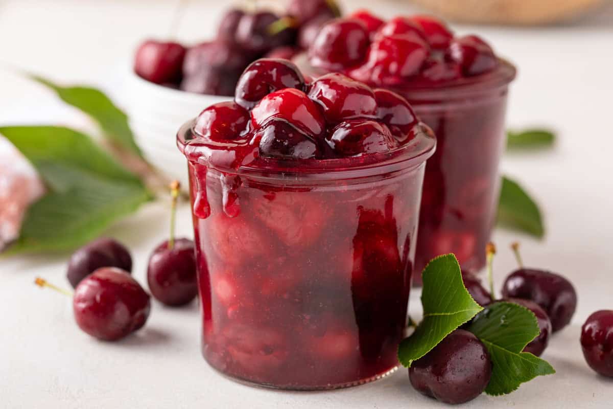 cherry pie filling in a glass jar on a countertop.