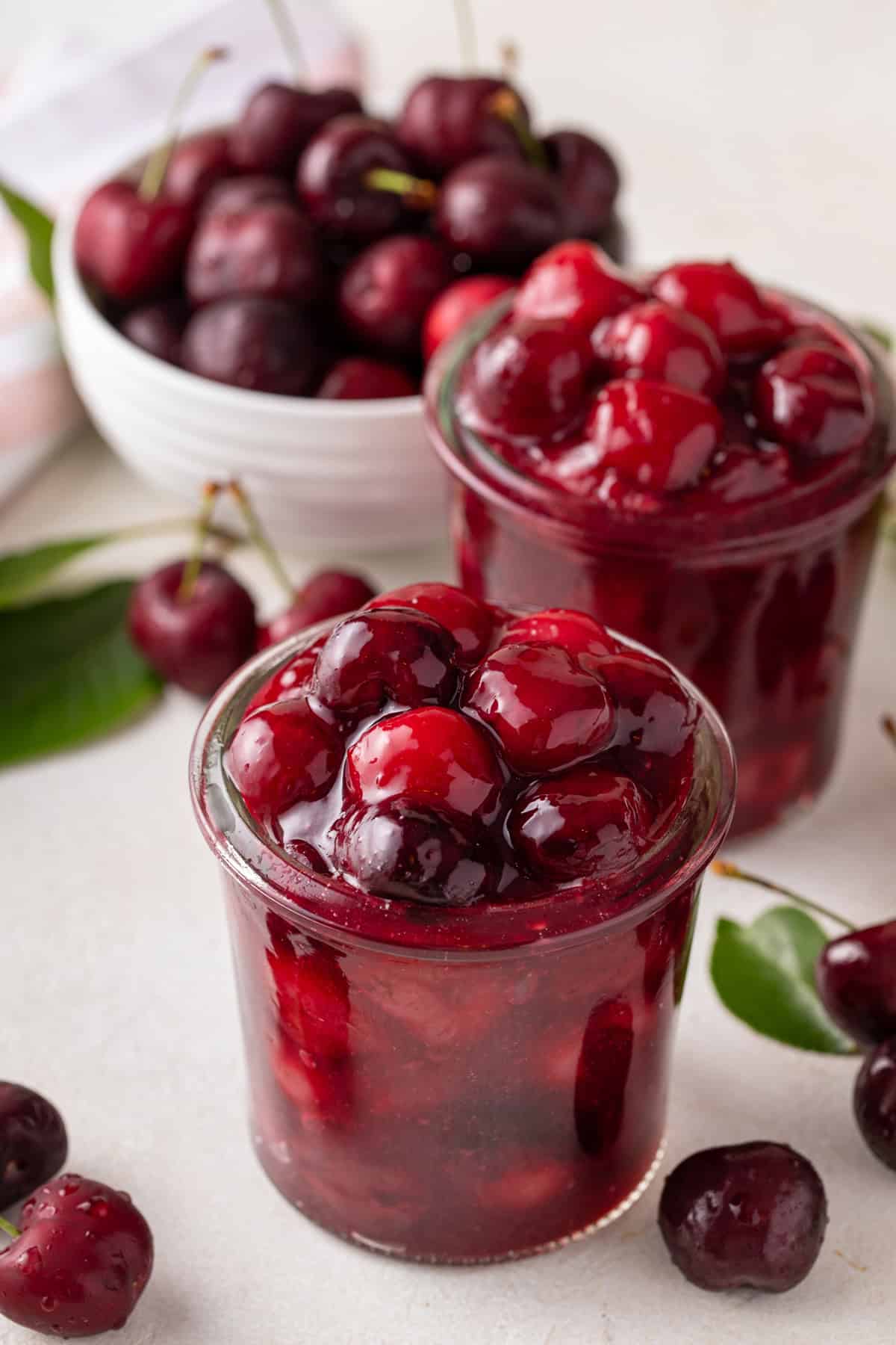 Two glass jars filled with homemade cherry pie filling.