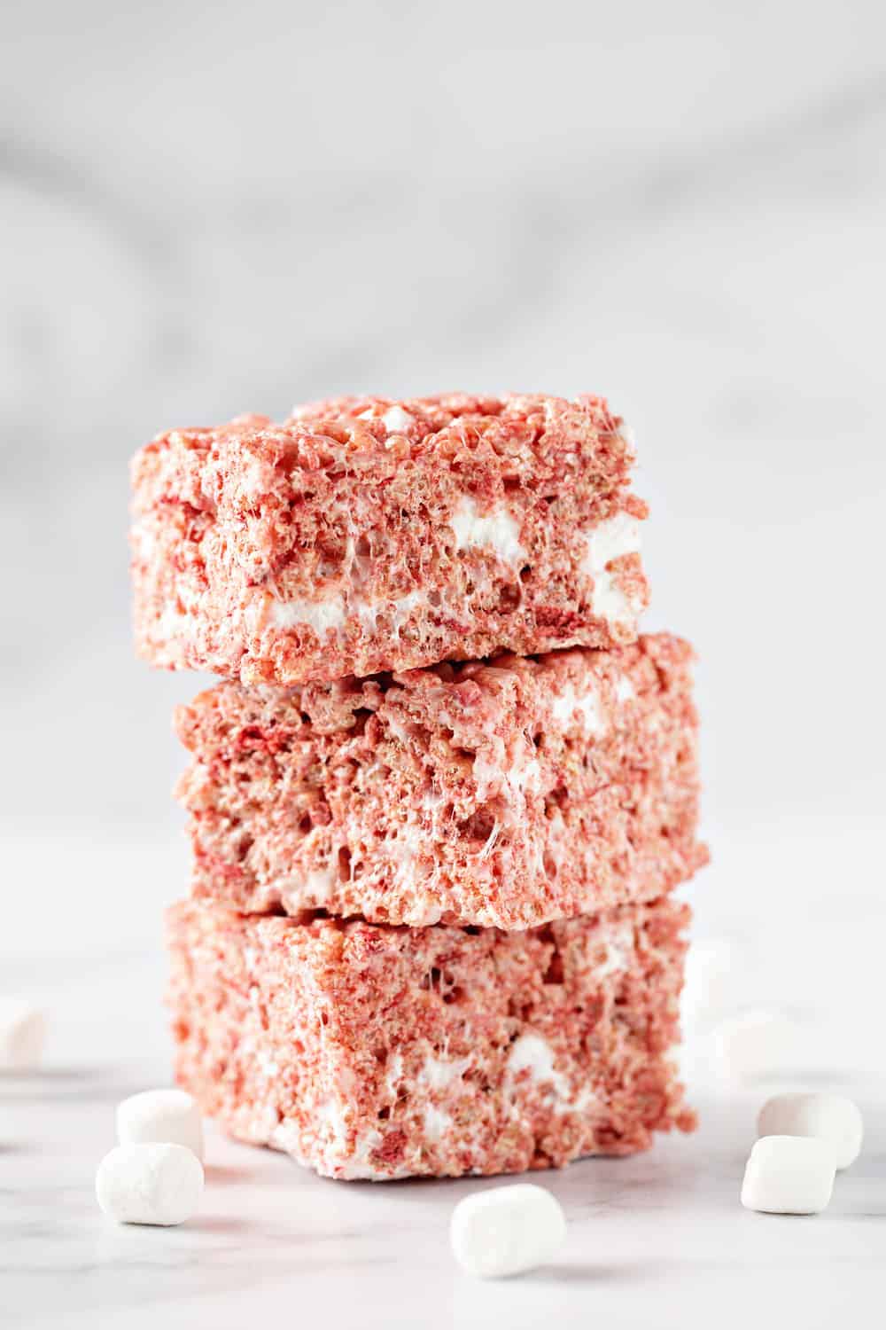 Strawberry Rice Krispie Treats are perfectly pink and full of flavor. Top them with fluffy buttercream frosting and fresh strawberries.