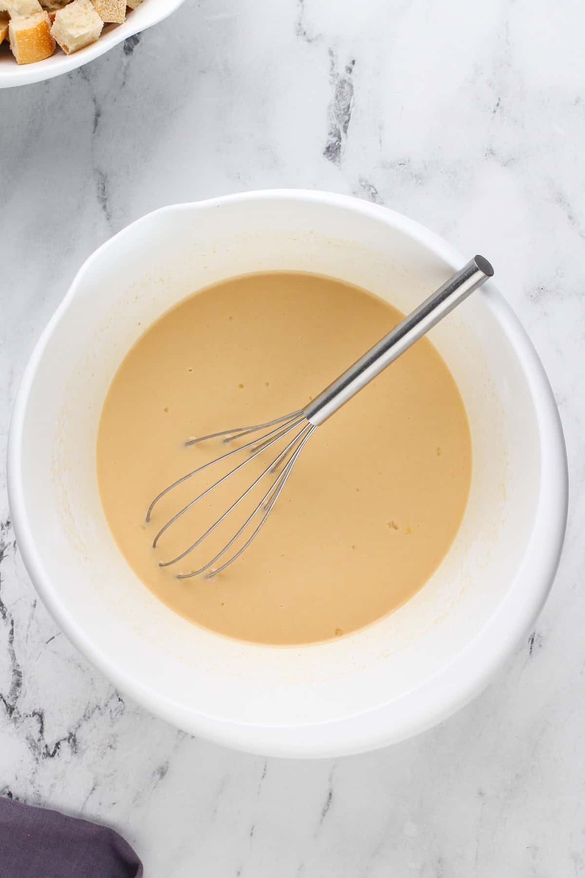 Custard for irish bread pudding whisked in a white bowl.