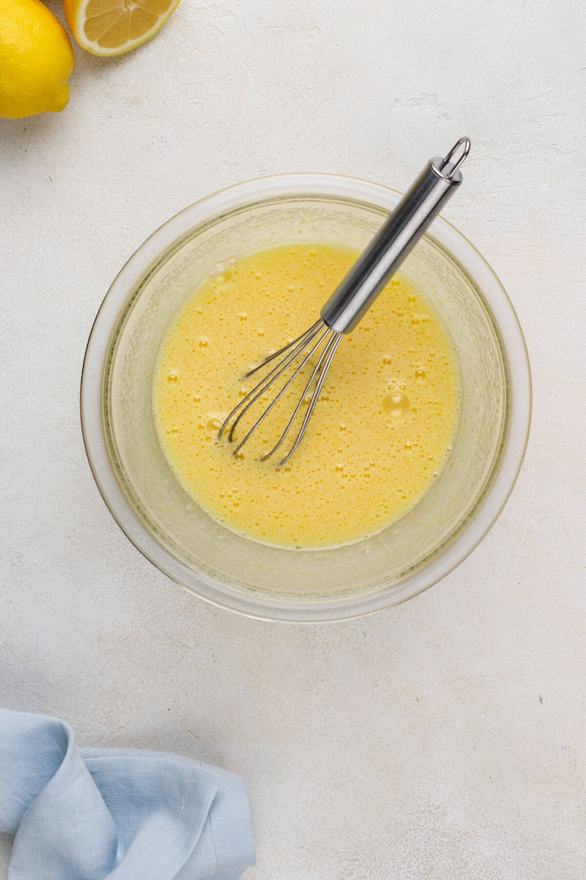Ingredients for microwave lemon curd whisked in a glass bowl.