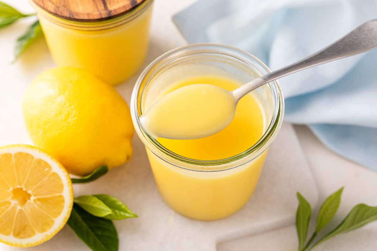 Jar of microwave lemon curd with a spoonful of the curd set on top.