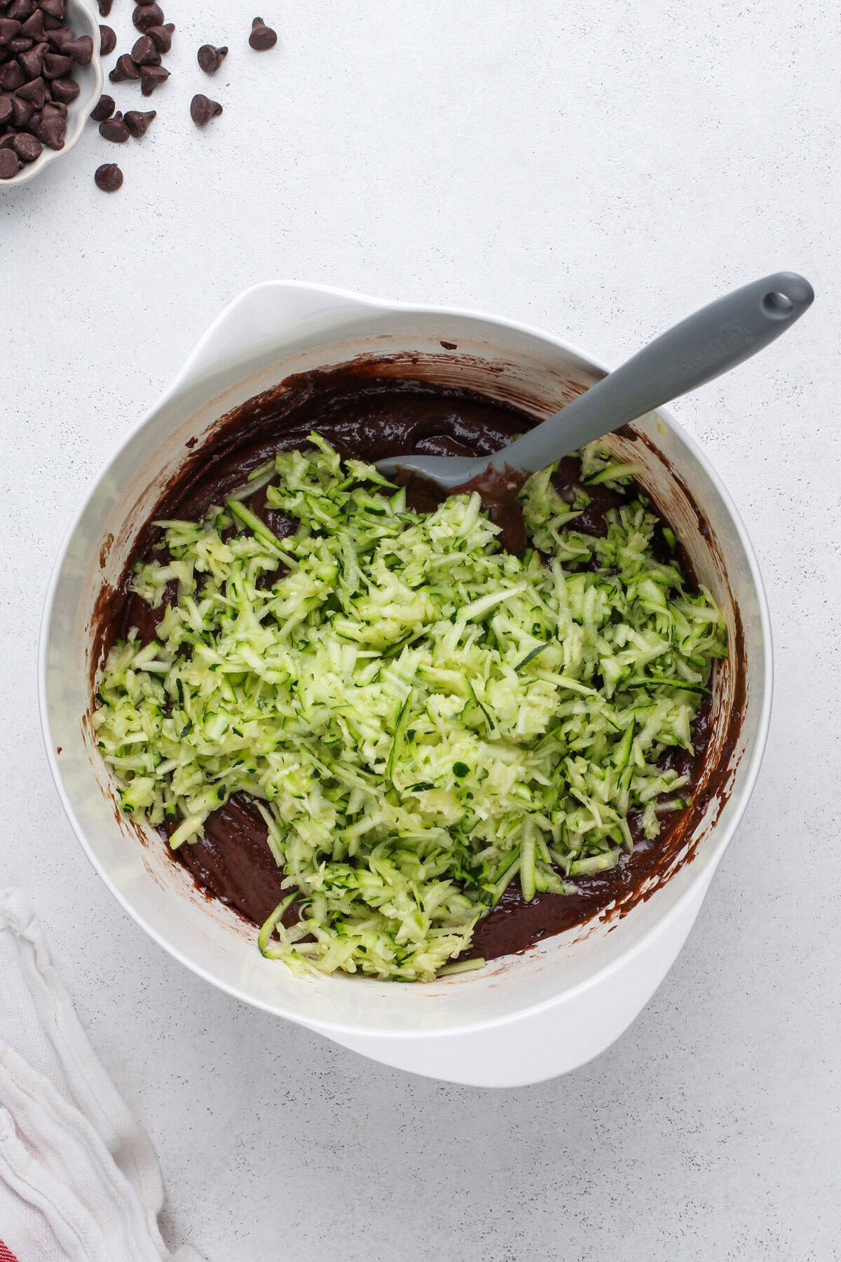 Grated zucchini being added to chocolate muffin batter.