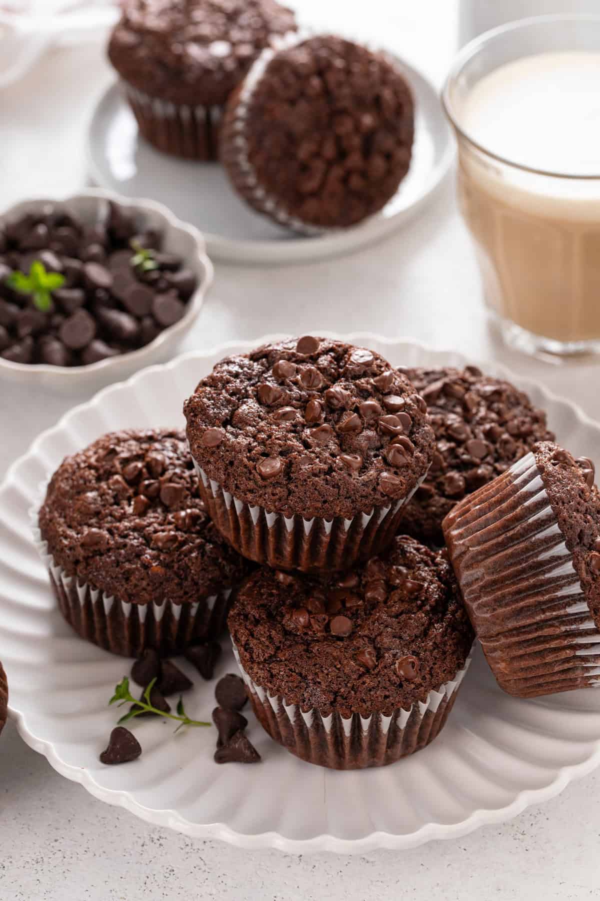 Chocolate zucchini muffins stacked on a white platter.