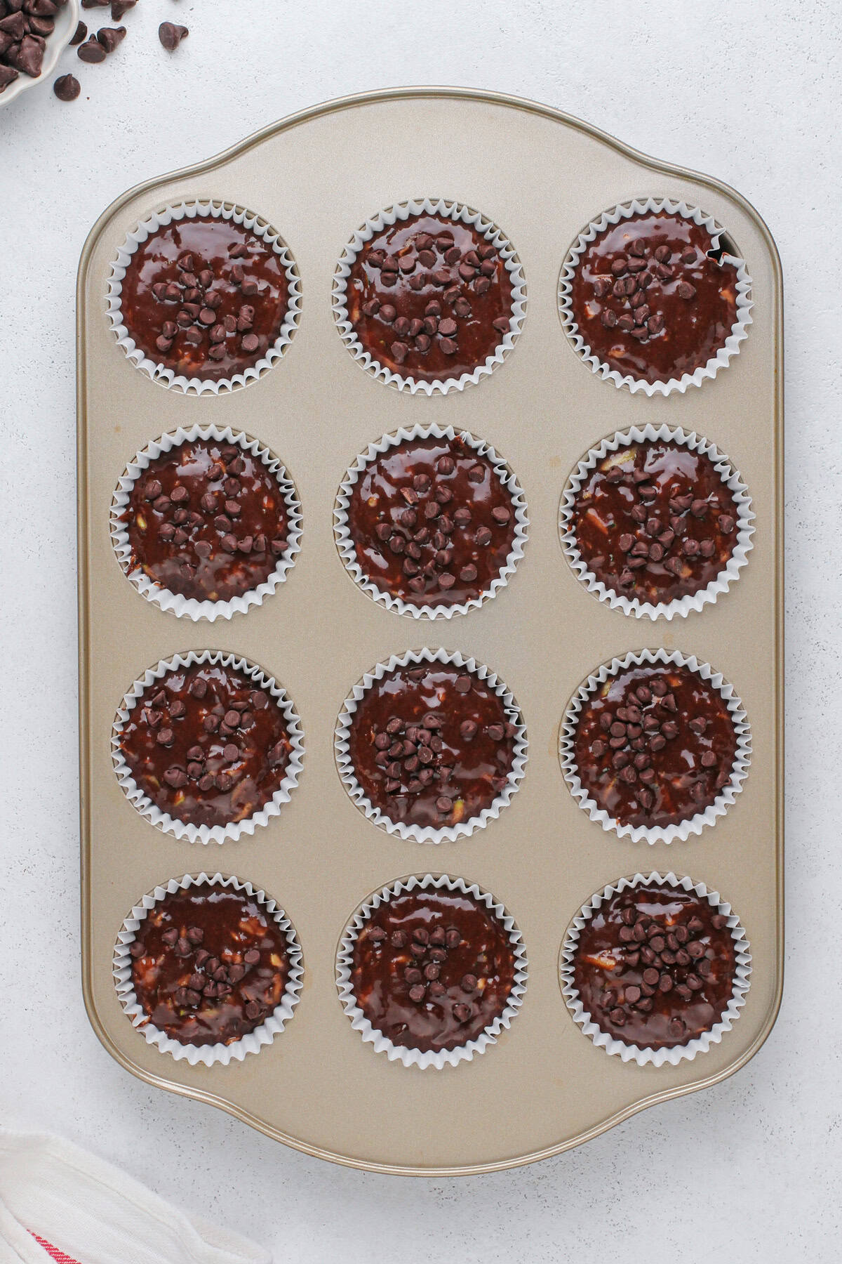 Unbaked chocolate zucchini muffins in a muffin tin, ready to go in the oven.