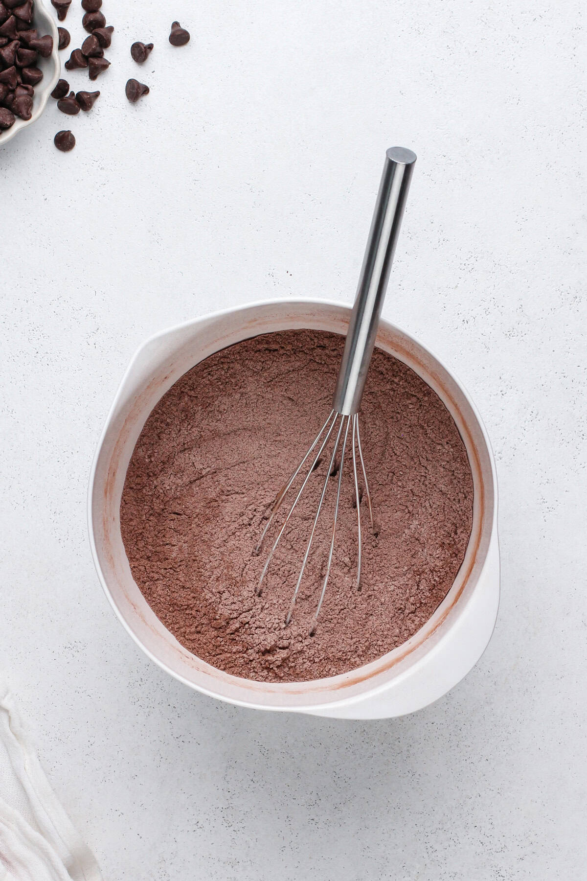 Dry ingredients for chocolate zucchini muffins whisked in a white bowl.