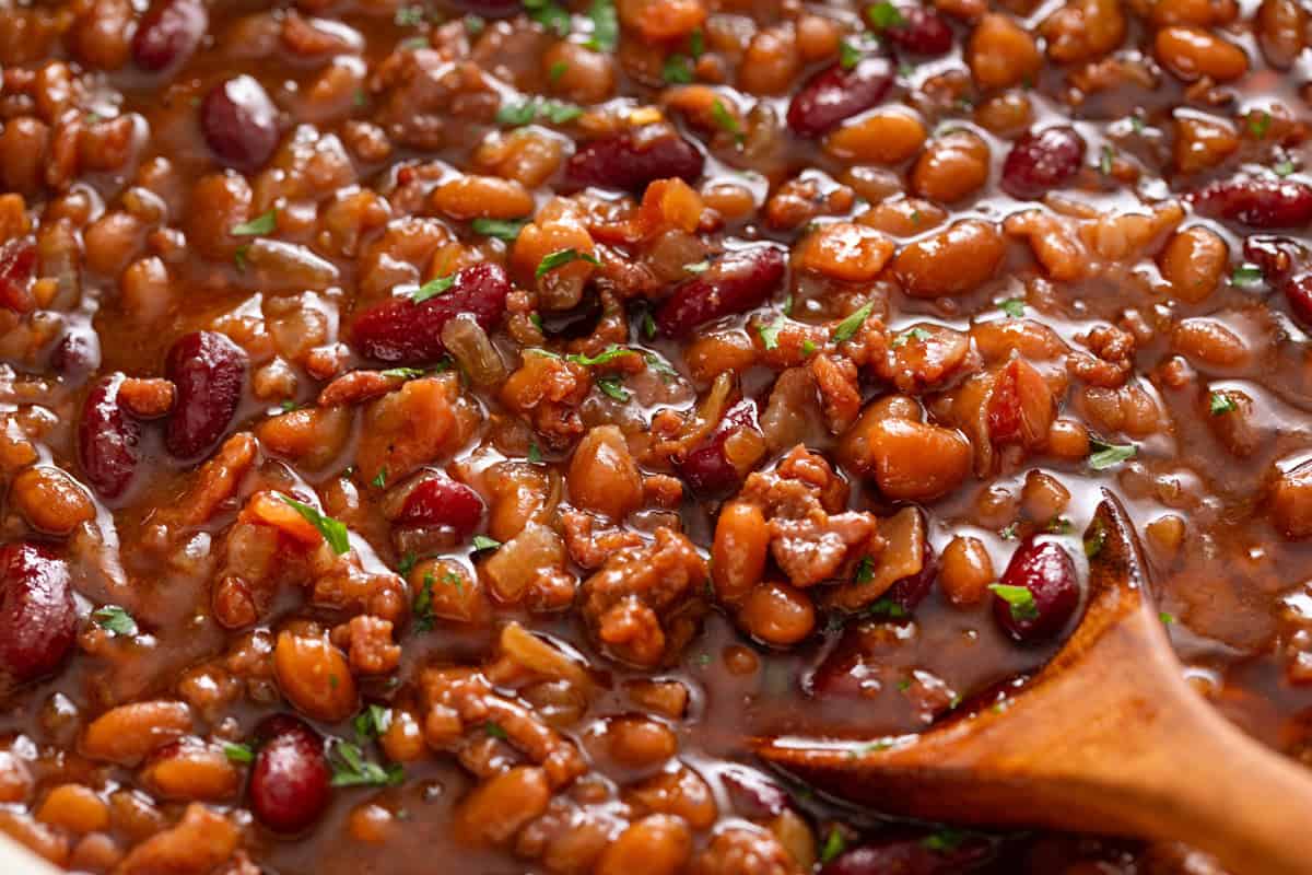 Close up image of a wooden spoon in easy baked beans.
