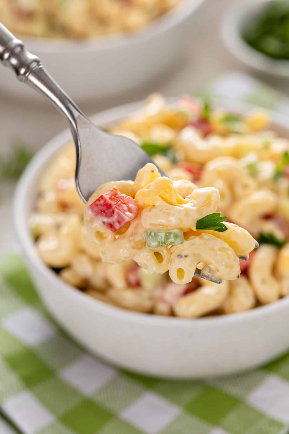 Fork holding up a bite of amish macaroni salad to the camera.