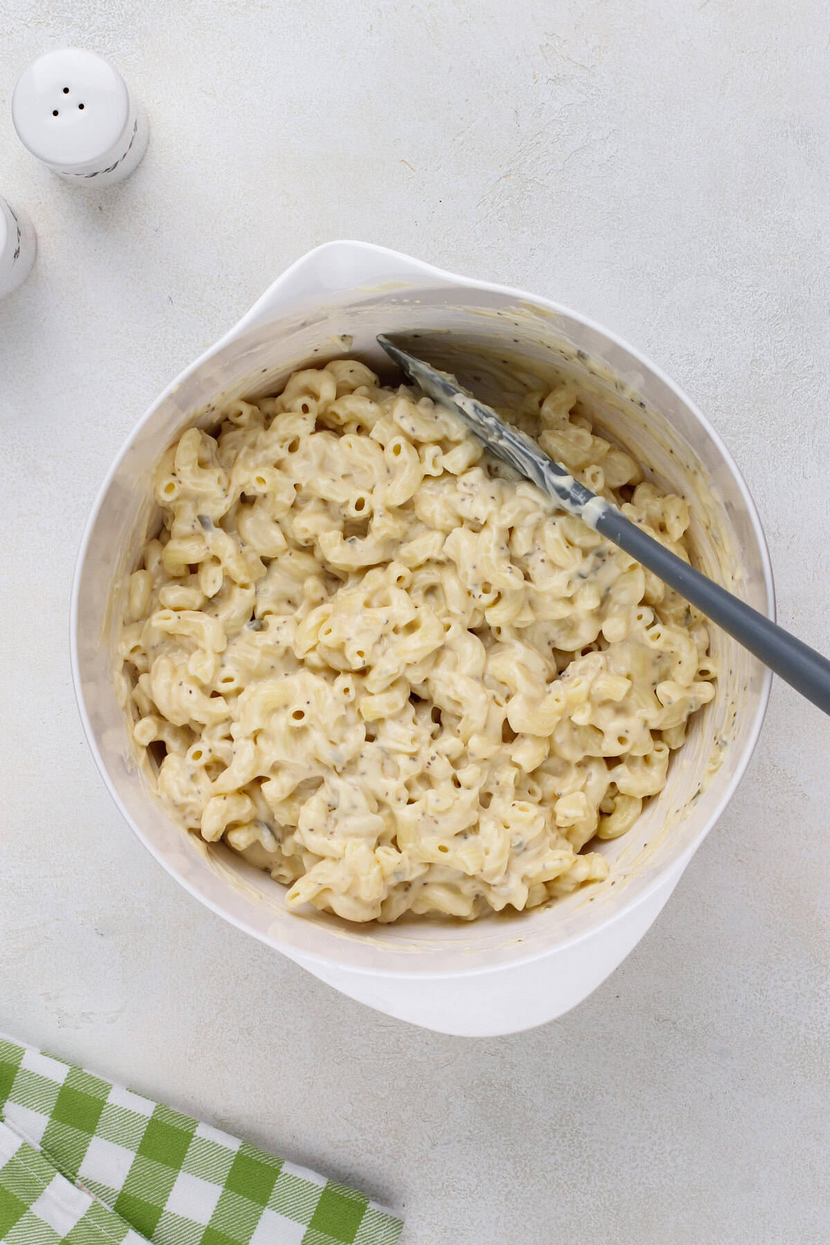 Cooked elbow macaroni mixed with salad dressing in a white bowl.