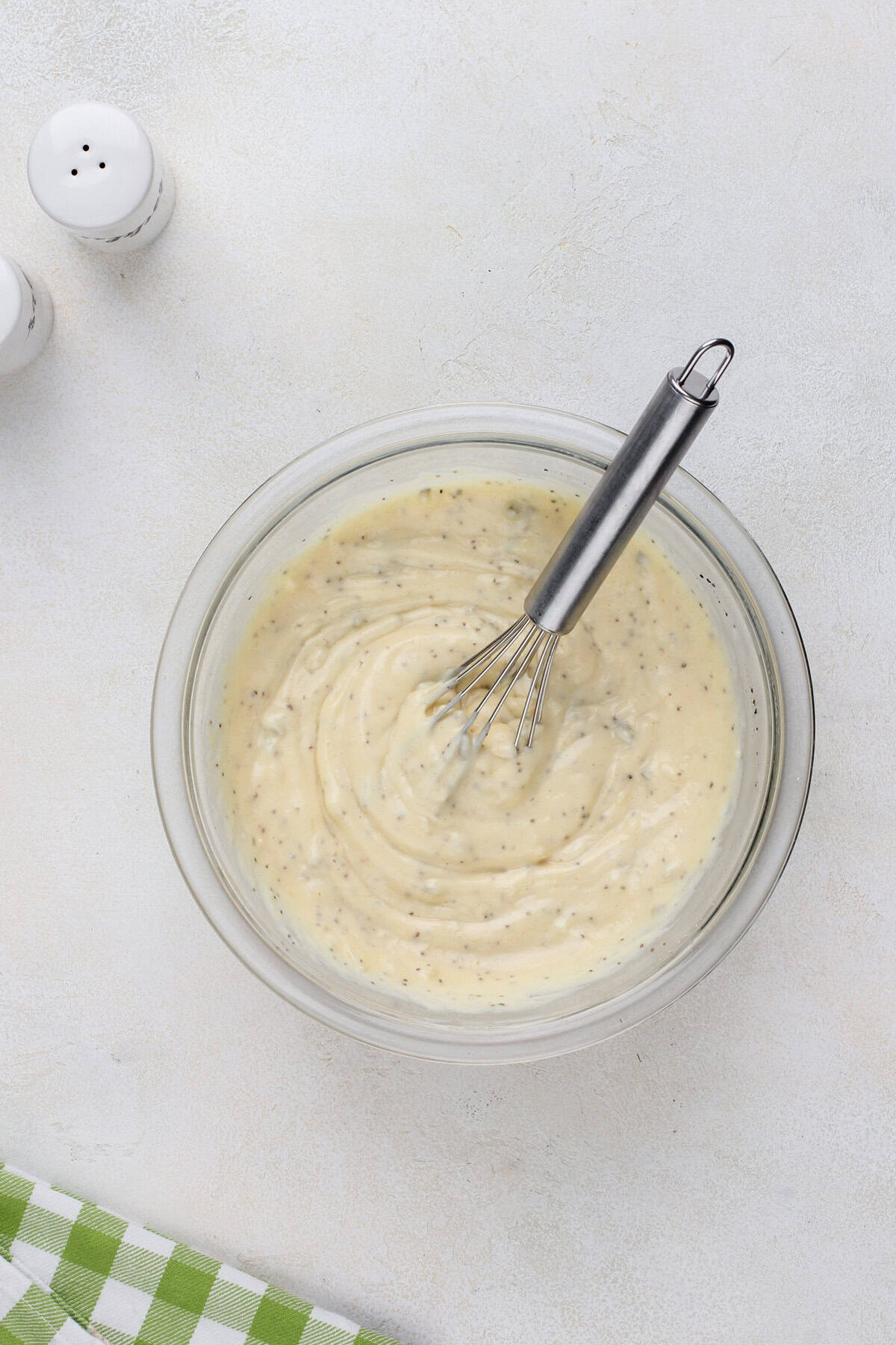 Dressing for macaroni salad whisked in a glass bowl.