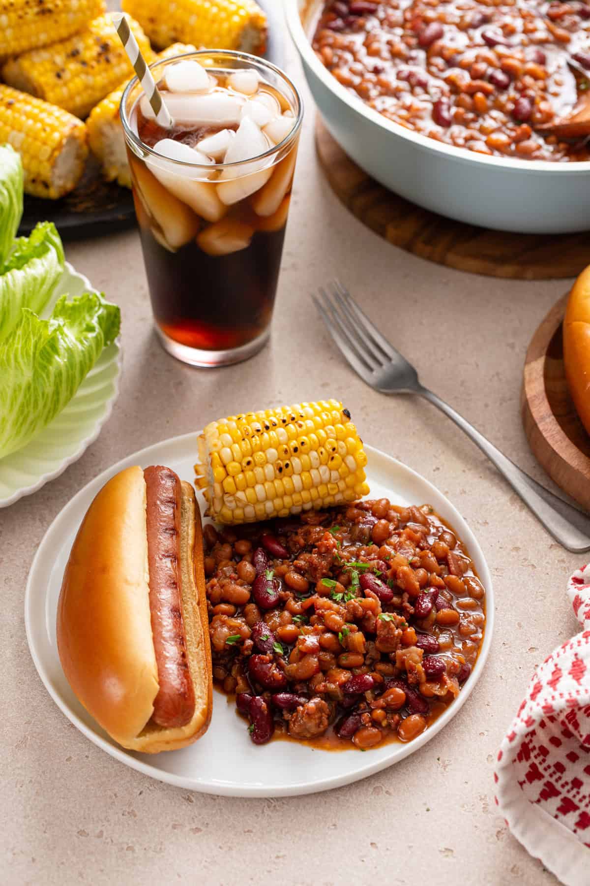 White plate holding easy baked beans, a hot dog, and corn.