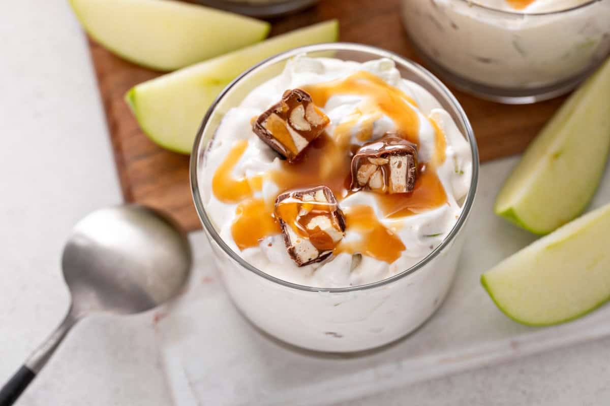 Close up of snickers salad topped with pieces of snickers bars and caramel sauce.