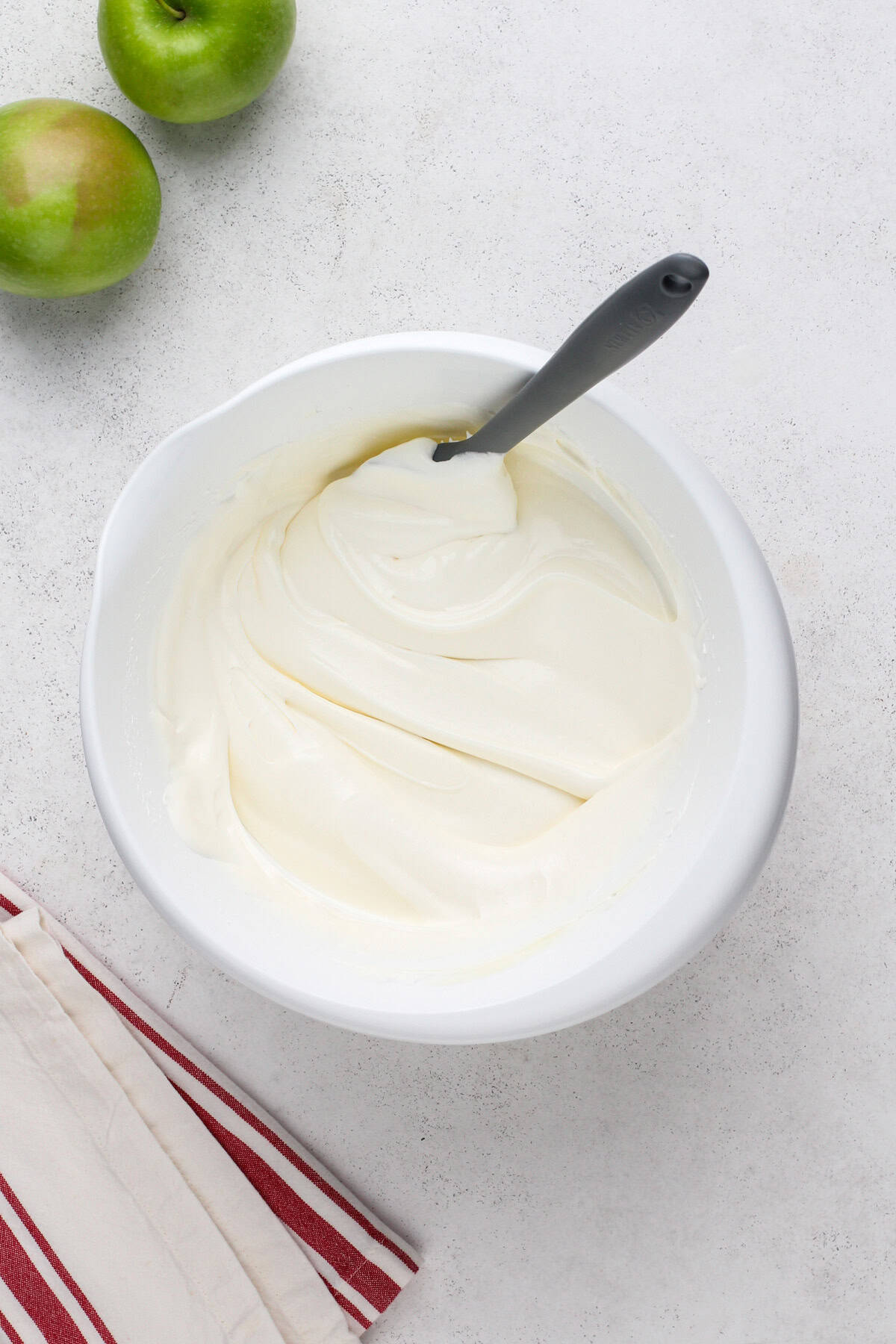 Cool whip folded into cheesecake pudding in a white bowl.
