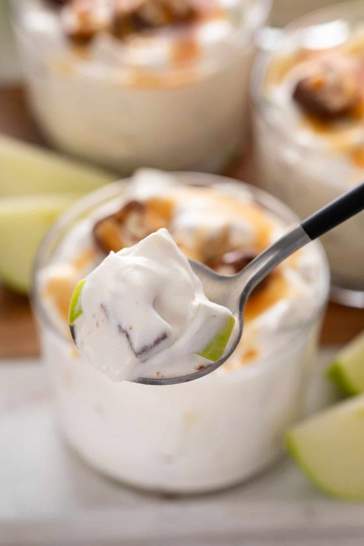 Spoon holding up a bite of caramel apple salad.