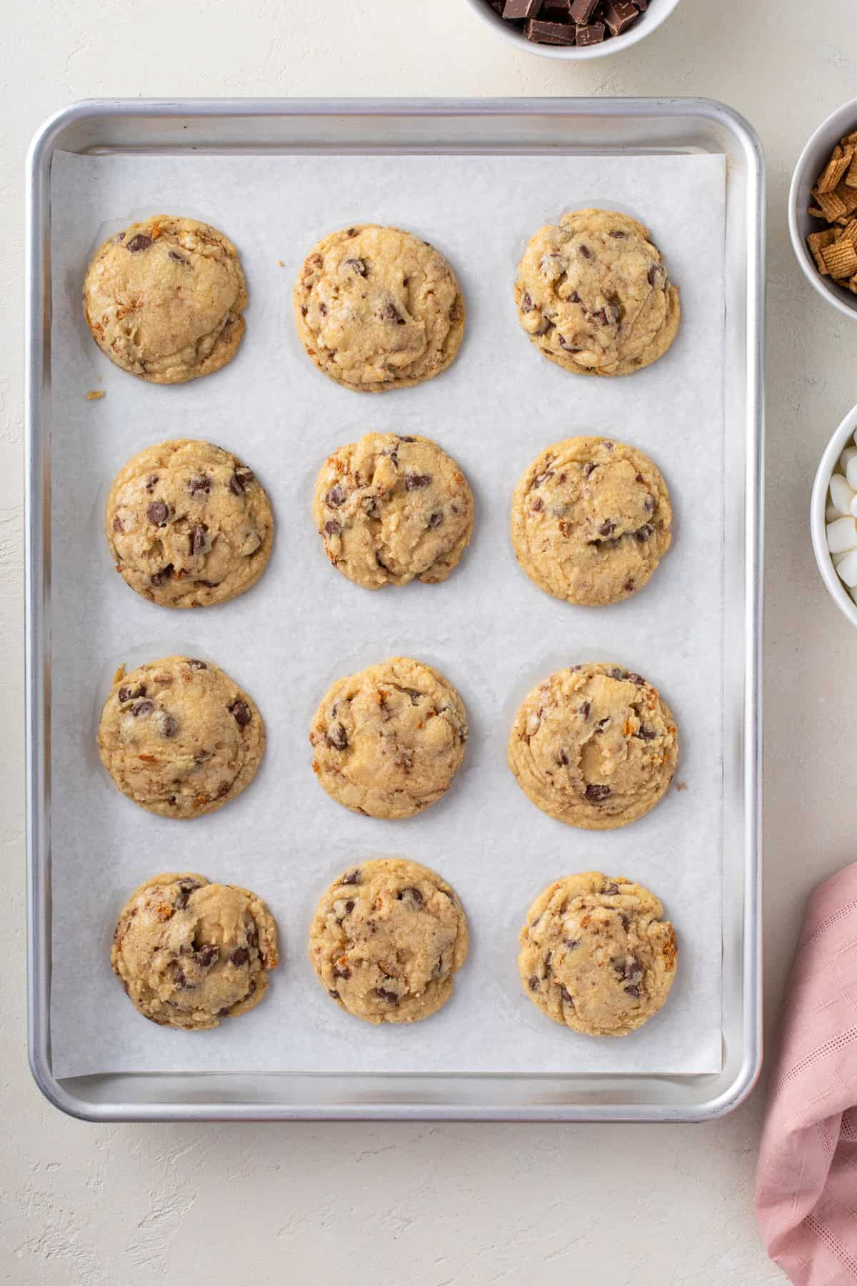 Partially baked s'mores cookies on a parchment-lined baking sheet.