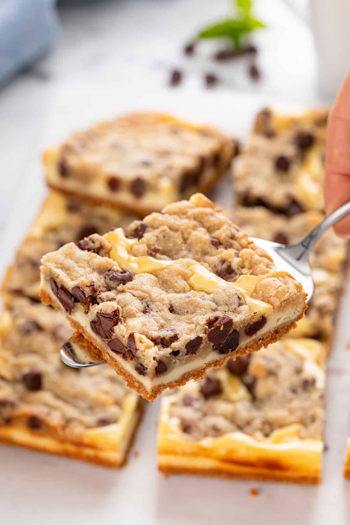 Cake server holding up a cookie dough cheesecake bar.