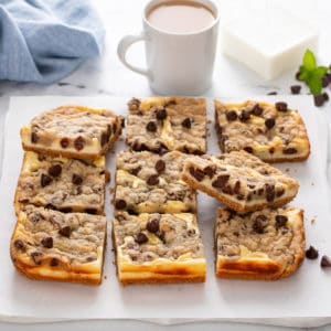 Slices of cookie dough cheesecake bars on a white board.