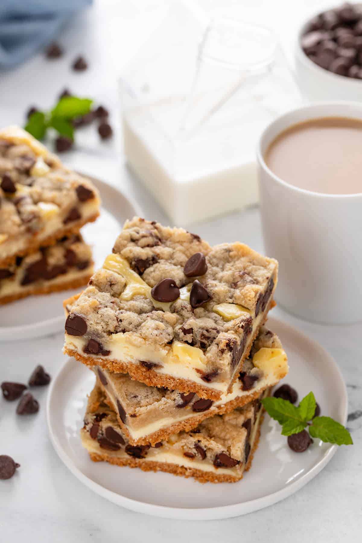 Three cookie dough cheesecake bars stacked on a white plate.