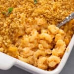 Close up of spoon in a corner of a casserole of baked mac and cheese.
