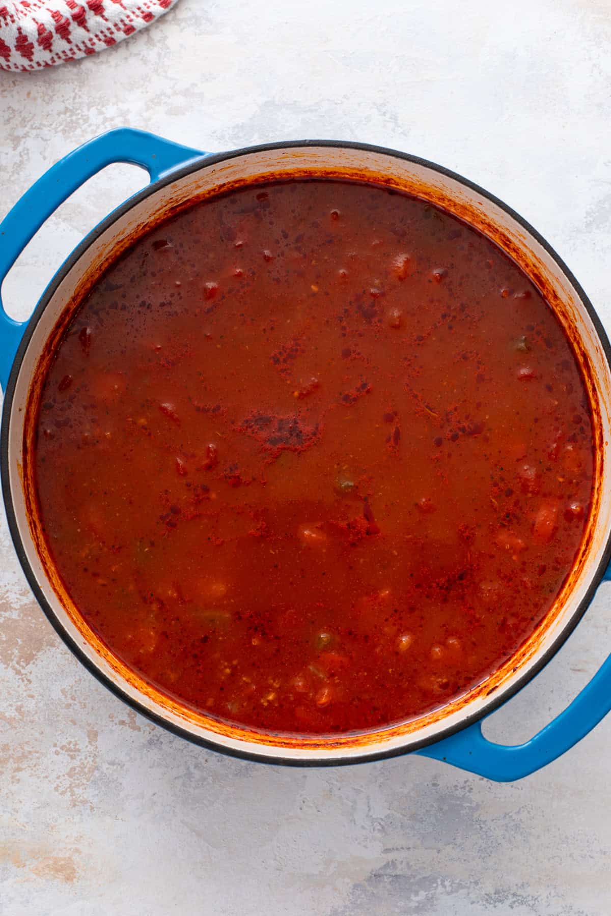 Tomato-based broth simmering in a blue dutch oven.