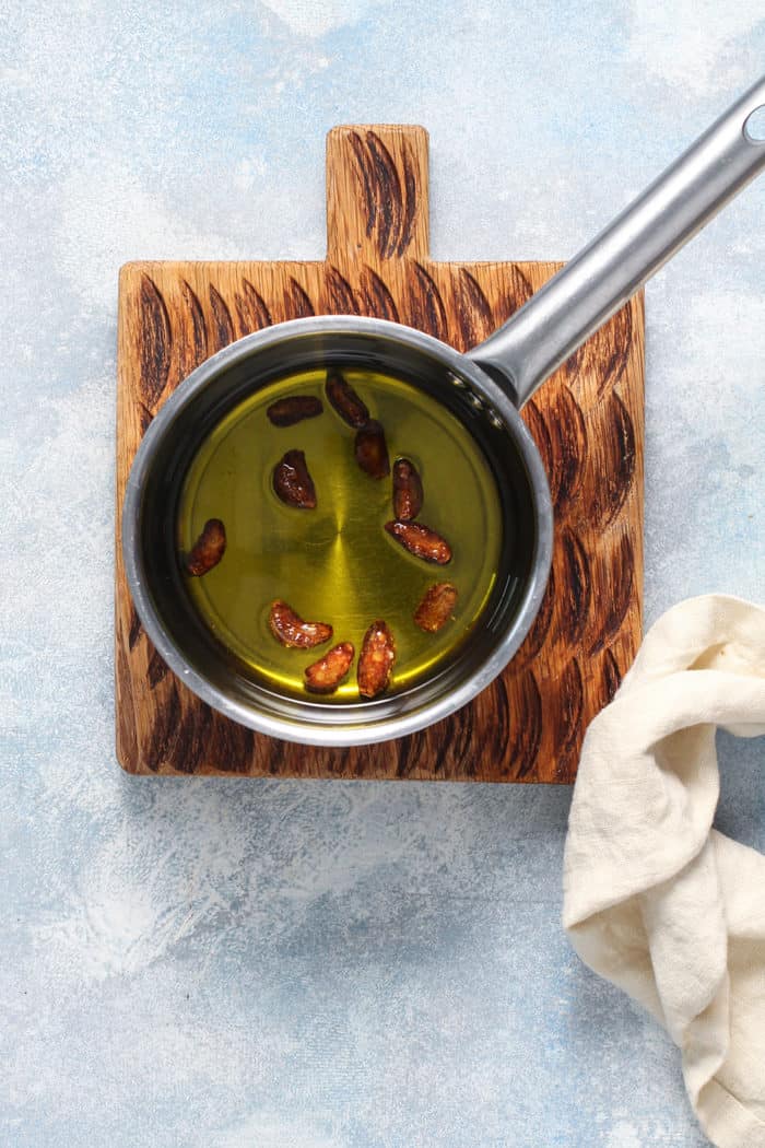 Roasted garlic cloves in oil in a small metal saucepot