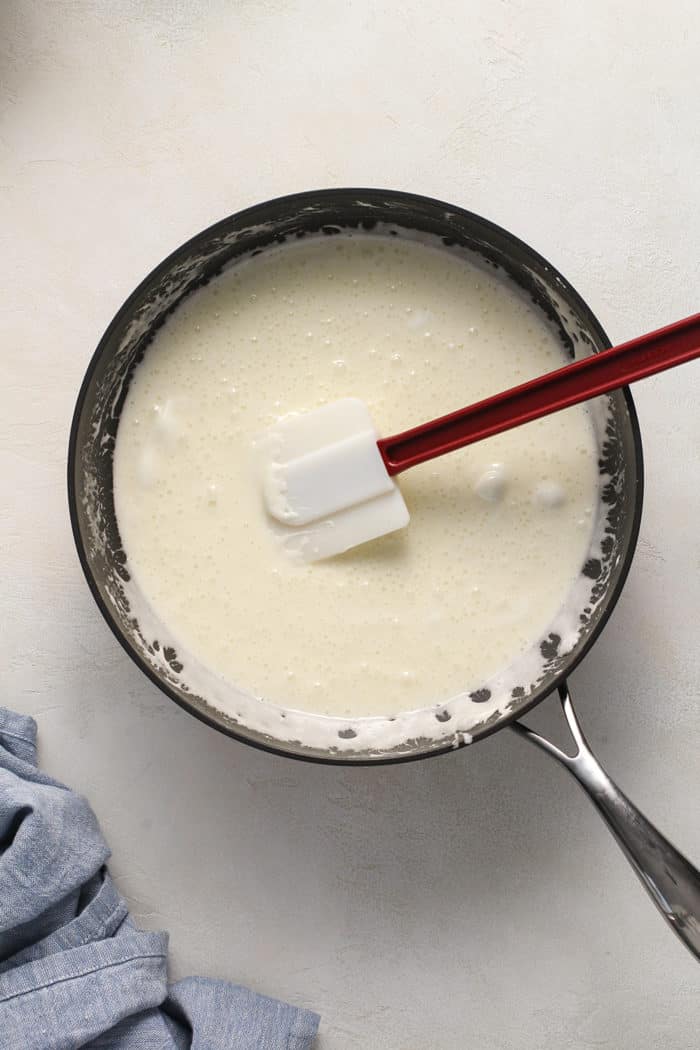 Rubber spatula stirring melted marshmallows in a black saucepan