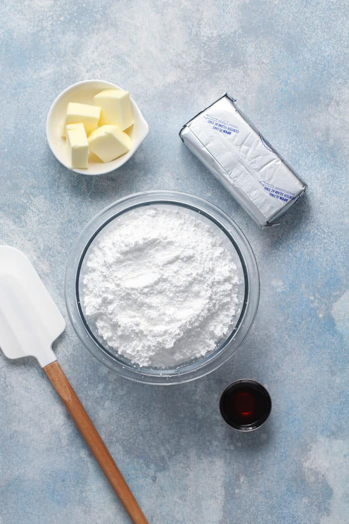Ingredients for cream cheese frosting arranged on a blue countertop