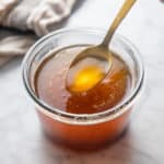 Spoon holding up a bit of brown butter over a jar of brown butter.