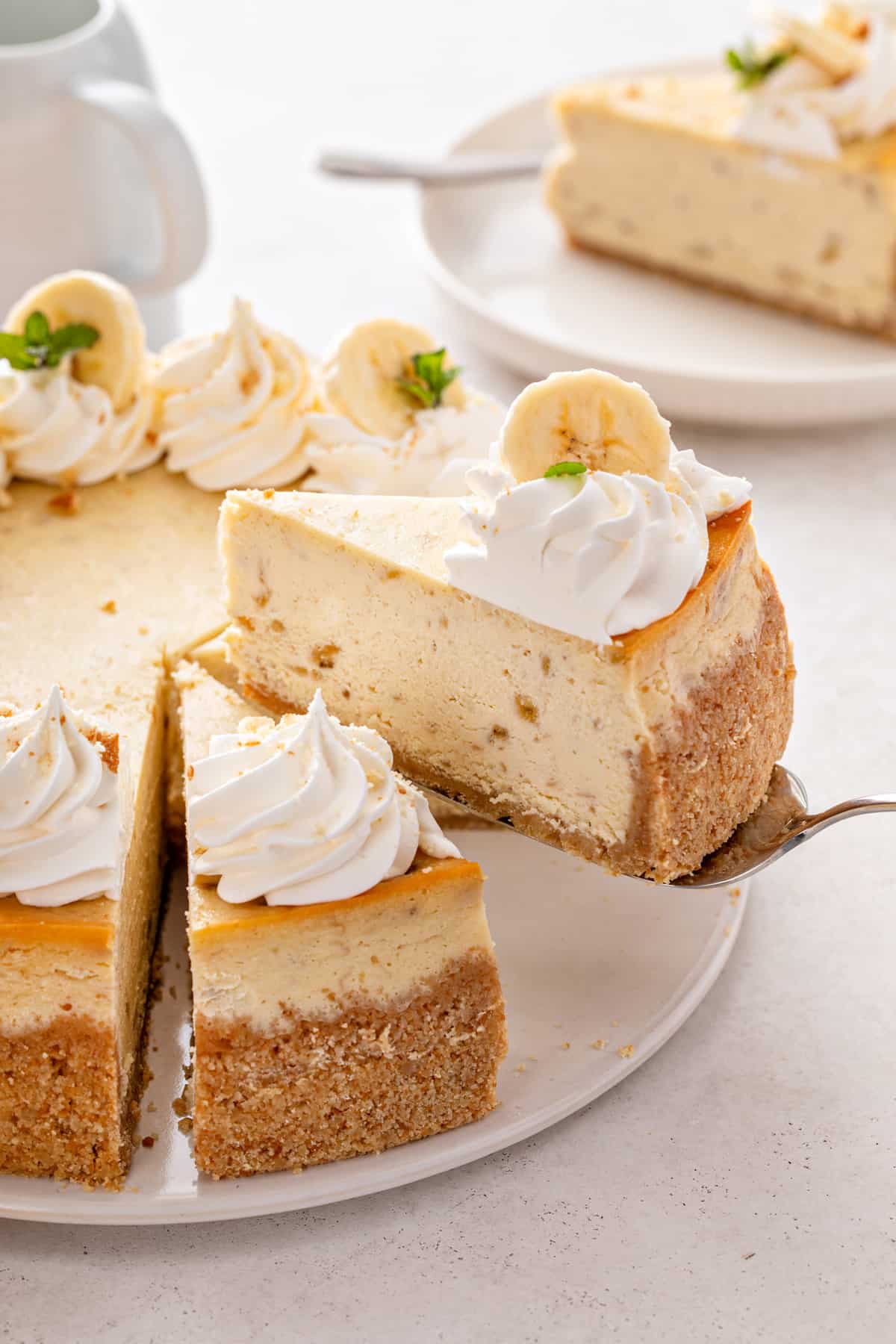 Cake server lifting up a slice of banana pudding cheesecake.