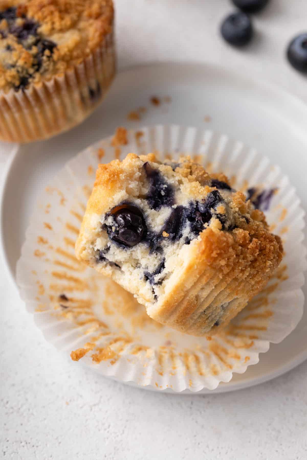Bite taken from a bisquick blueberry muffin on a white plate.