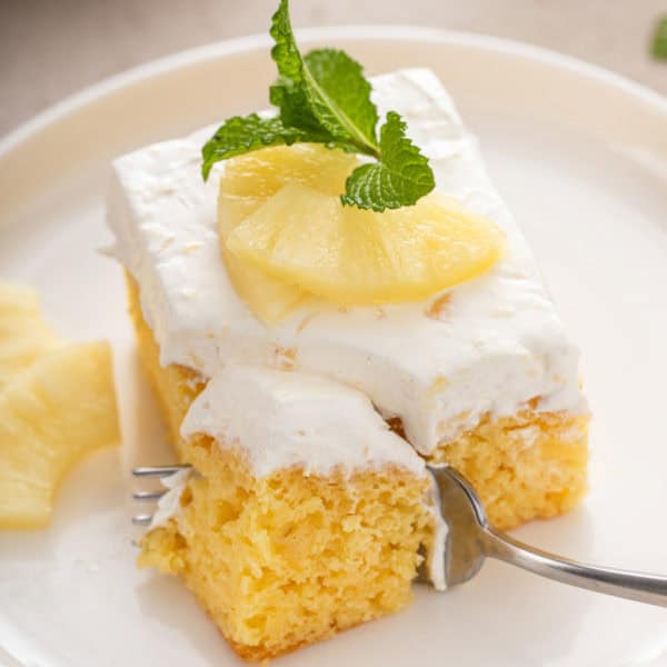 Fork cutting a bite from the corner of a slice of easy pineapple cake.