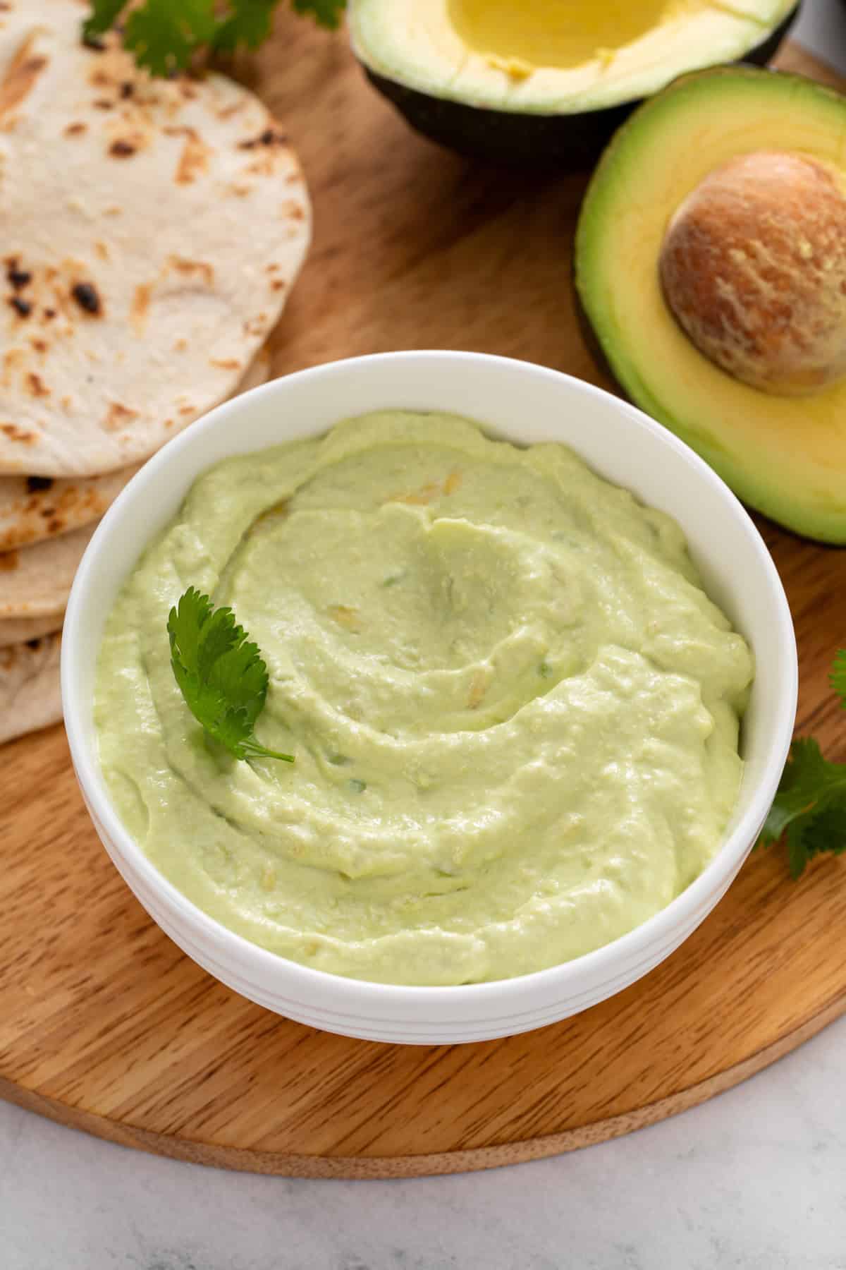 Close up image of avocado crema in a white bowl.