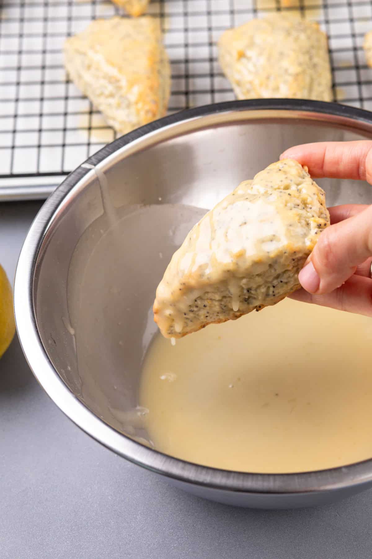 Hand dipping a lemon poppy seed scone in lemon glaze.