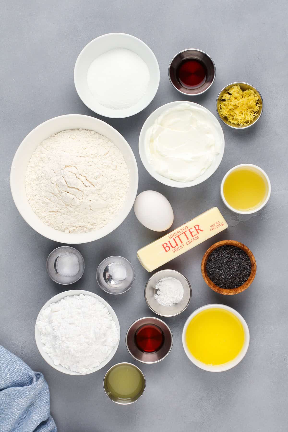 Ingredients for lemon poppy seed scones arranged on a gray countertop.