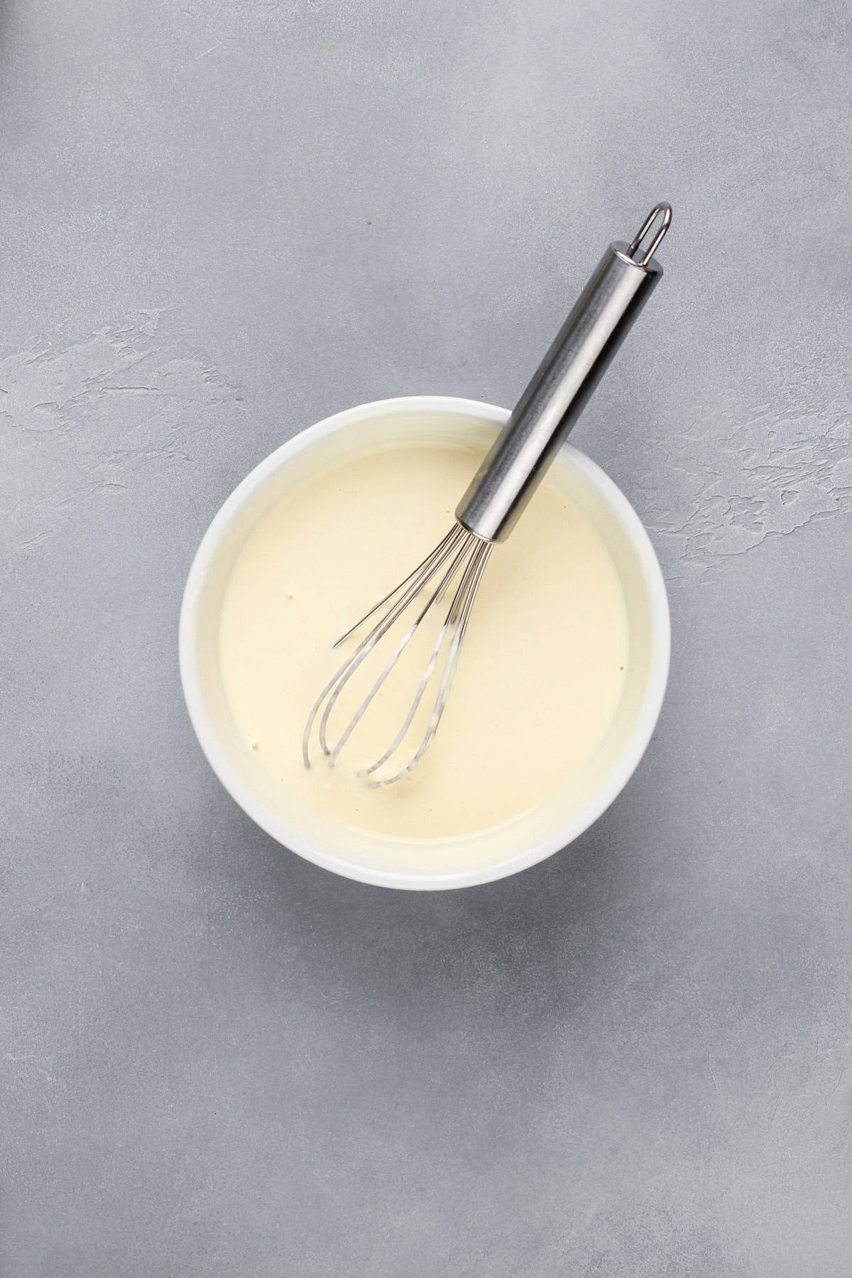Wet ingredients for lemon poppy seed scones being whisked in a small bowl.